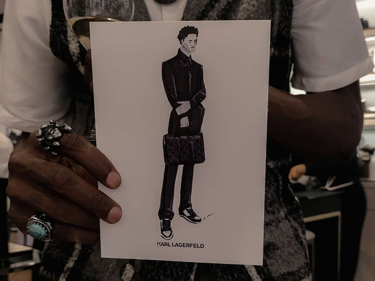 A photo of a guest holding a fashion illustration done as a live event sketch at an in store event for Karl Lagerfeld. Outfits were predrawn and printed with guest's faces customized live. Artist BY HANLI