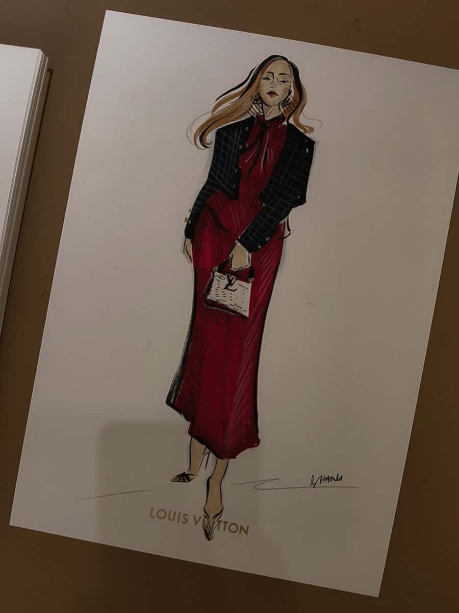 A photo of a fashion illustration done as a live event sketch of a guest in a red dress at a Louis Vuitton in store event by artist Hanli
