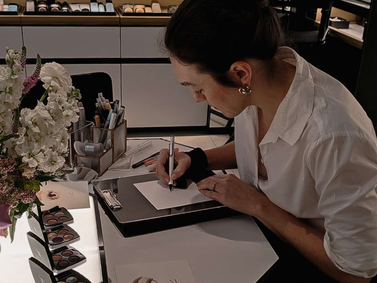 Photo of live event artist and fashion illustrator, Hanli, sketching guests at an in store Chanel event.