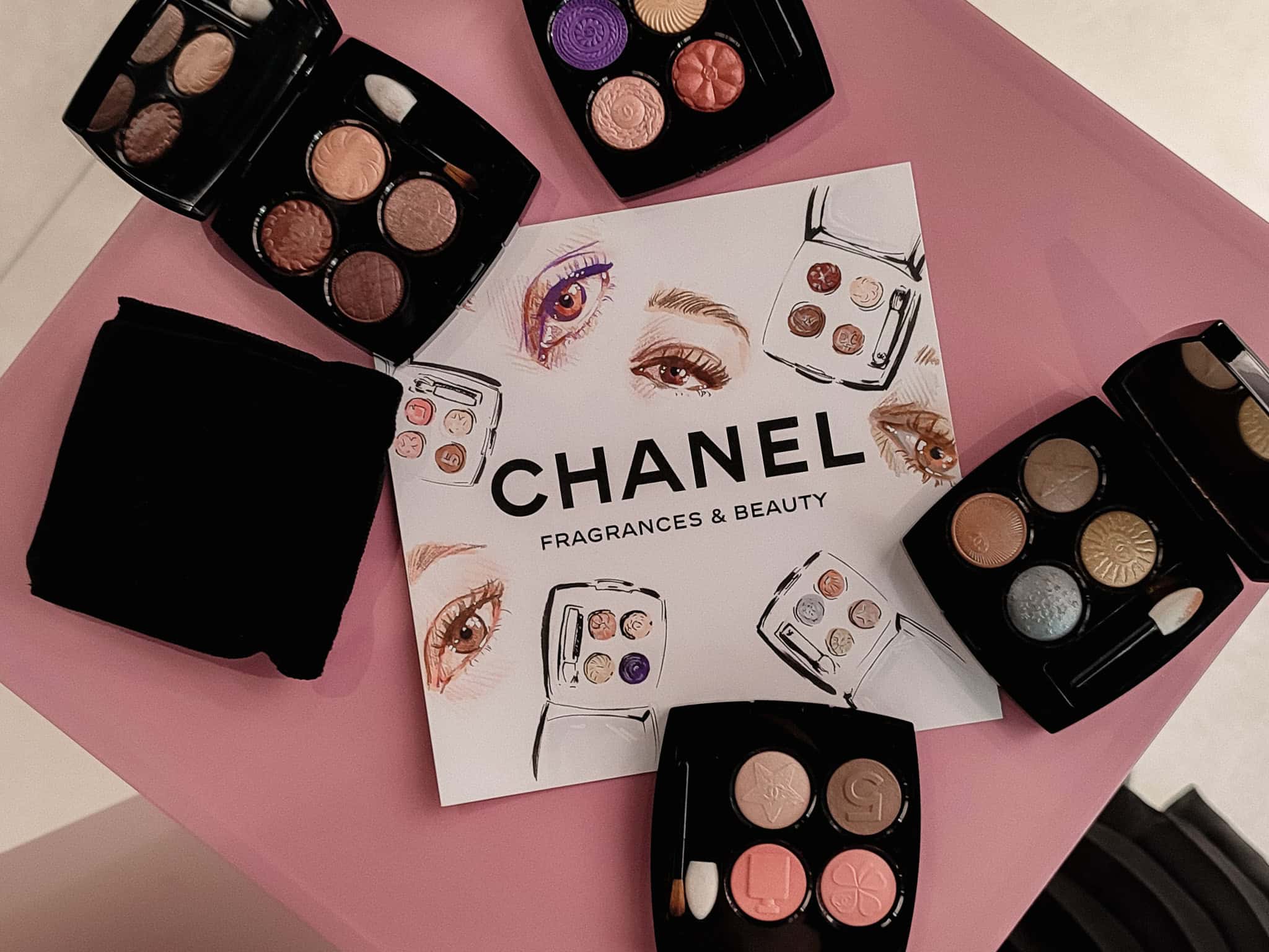 A flatlay of CHANEL Les 4 Ombres Bouton eyeshadow palettes and a eye and beauty product sketches on a CHANEL paper at an in store event in Cape Town by artist, Hanli.